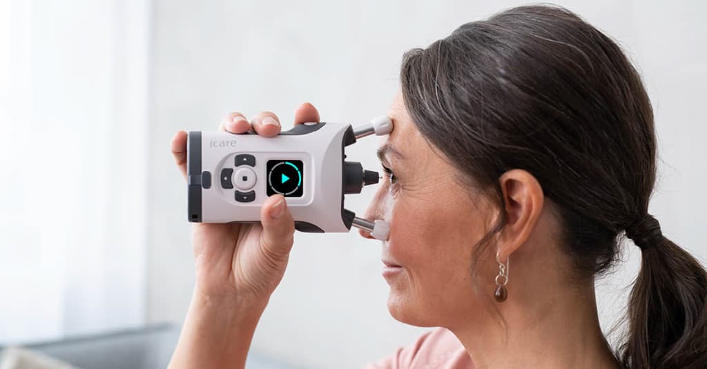 Woman comfortably using the iCare HOME2 at home on her couch